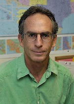 Photo of Charles Postel in front of a world map